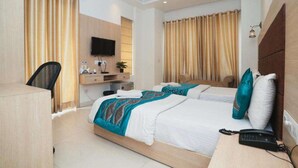A hotel room with a bed, a desk, a chair, a TV, and a telephone. - Interglobe Oasis (Gurugram)