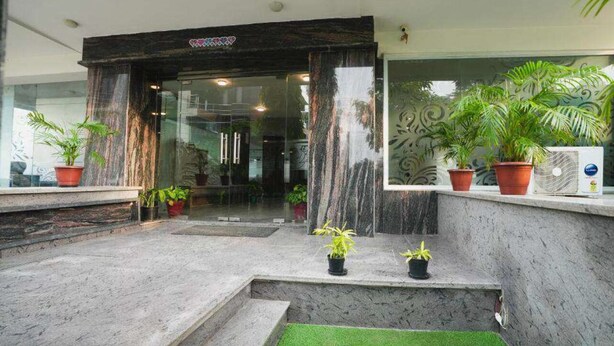 A reception area with a marble entrance, potted plants, and a small artificial green space. - Interglobe Oasis (Gurugram)