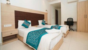 Habitación de hotel con dos camas, un escritorio, una silla y un armario.