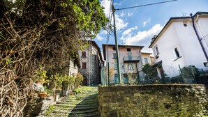 A narrow stone staircase leading up to a building with a white facade and a green fence. - Casa Caramello (Palanzo)