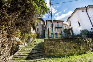 A narrow stone staircase leading up to a building with a white facade and a green fence.