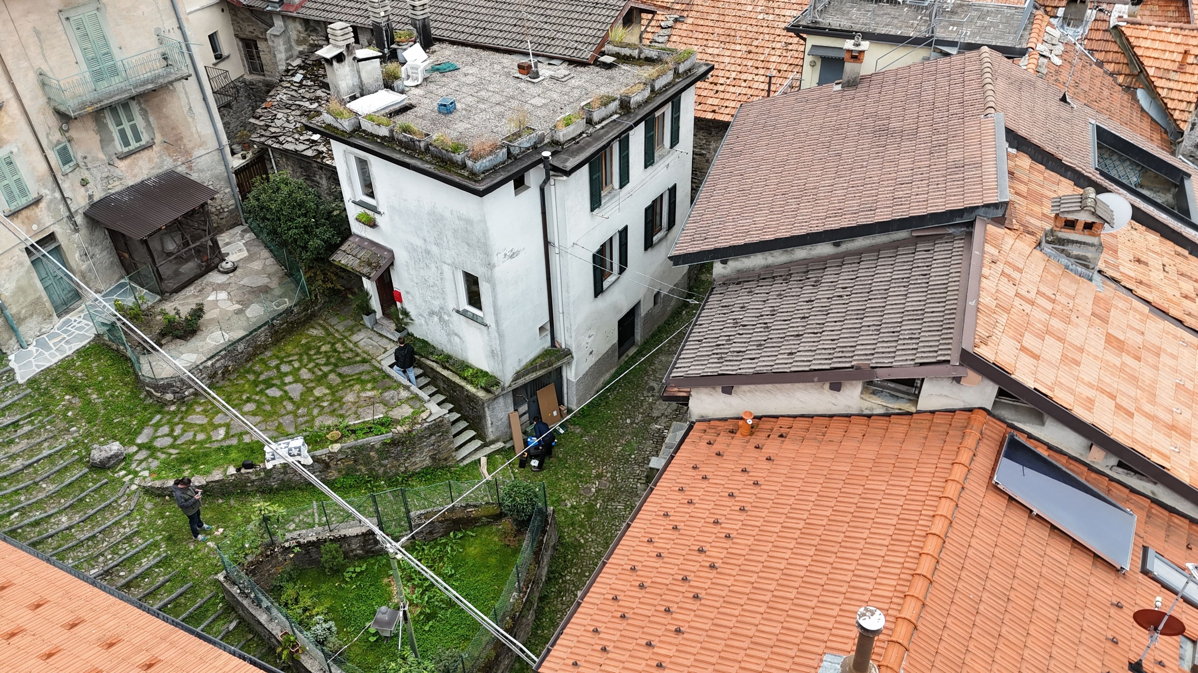 A courtyard with a building featuring a stone staircase, a small garden area, and a metal fence.