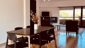 Een moderne eetruimte met een donker houten tafel en zwarte stoelen, een flatscreen televisie en een groot raam met uitzicht.