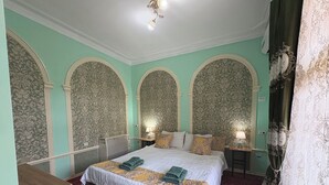 Habitación de hotel con una cama grande, dos mesitas de noche, un escritorio y una alfombra estampada.