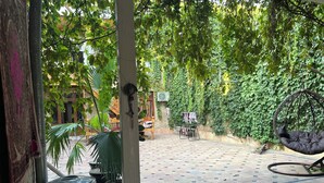 Un patio con una hamaca colgante, plantas en macetas y suelo de baldosas.