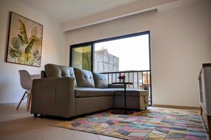 Un soggiorno moderno con un divano, un tavolino, una poltrona e un'ampia finestra.