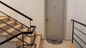 Una escalera con barandilla que lleva a una puerta con felpudo.