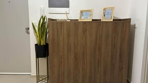 Una recepción con detalles de madera, una planta en maceta y dos certificados o premios enmarcados.