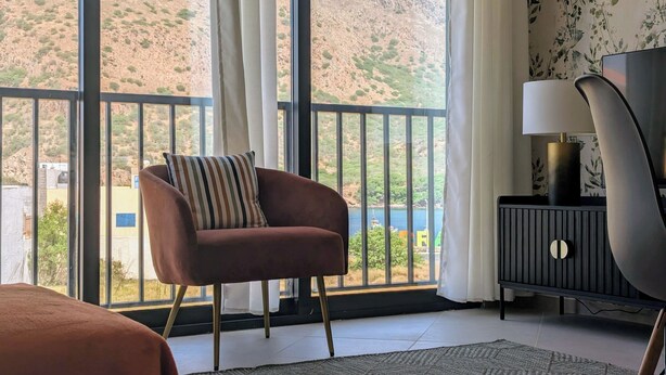 A room with a large window, a chair, a bed, a lamp, and a small table. - Tarrafal Bay · 1Bdr Apt · Sea view - 4 (Tarrafal)
