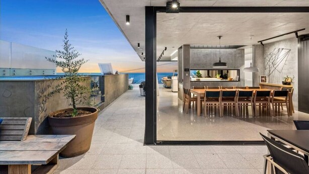 Una terraza moderna en la azotea con zona de comedor, plantas en macetas y vista al océano.