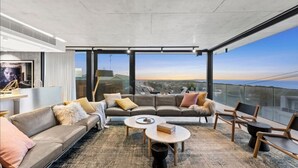 Una sala de estar moderna con un conjunto de sofá, una mesa de centro y sillones, con un ventanal que ofrece vistas a la ciudad.