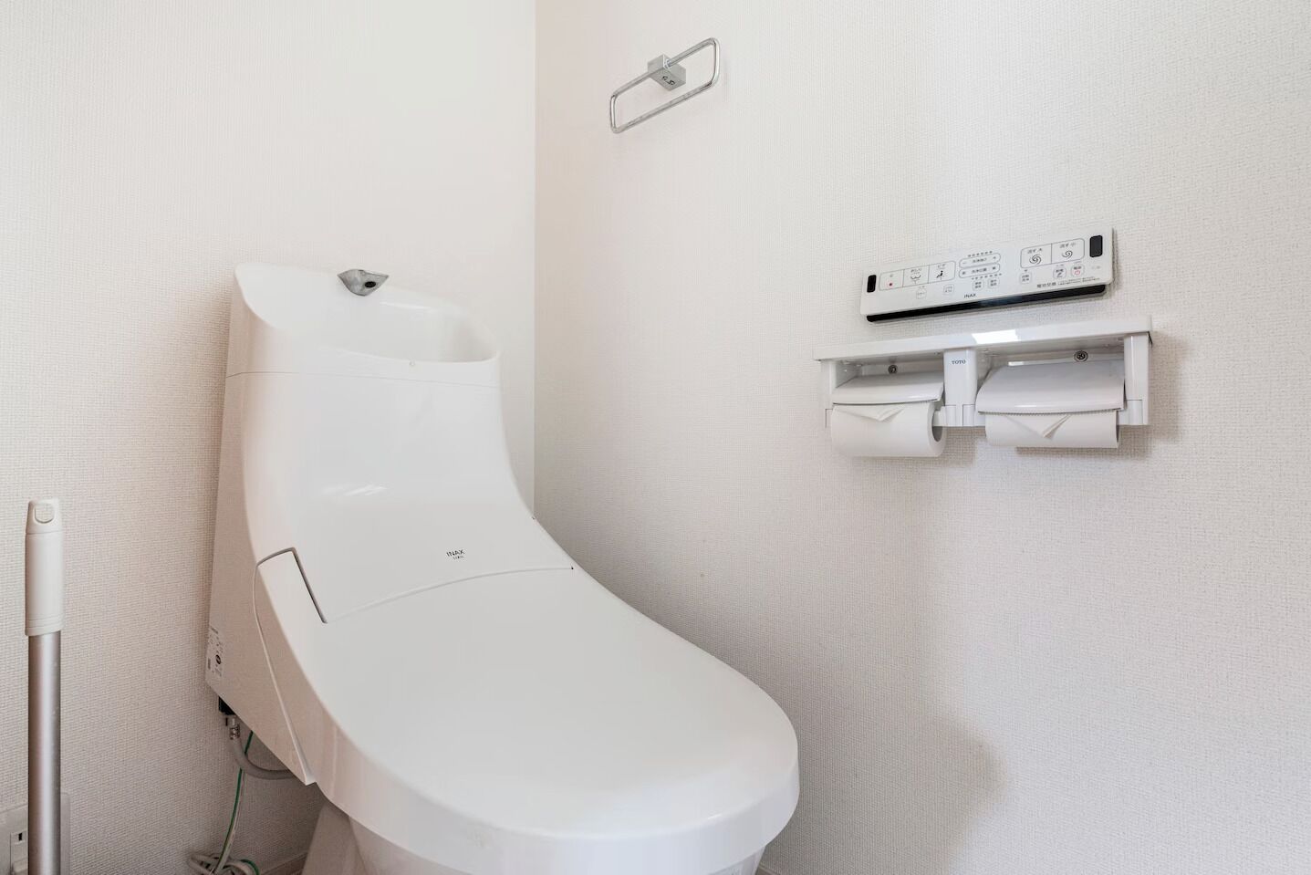 A modern toilet with a wall-mounted bidet and a toilet paper holder.