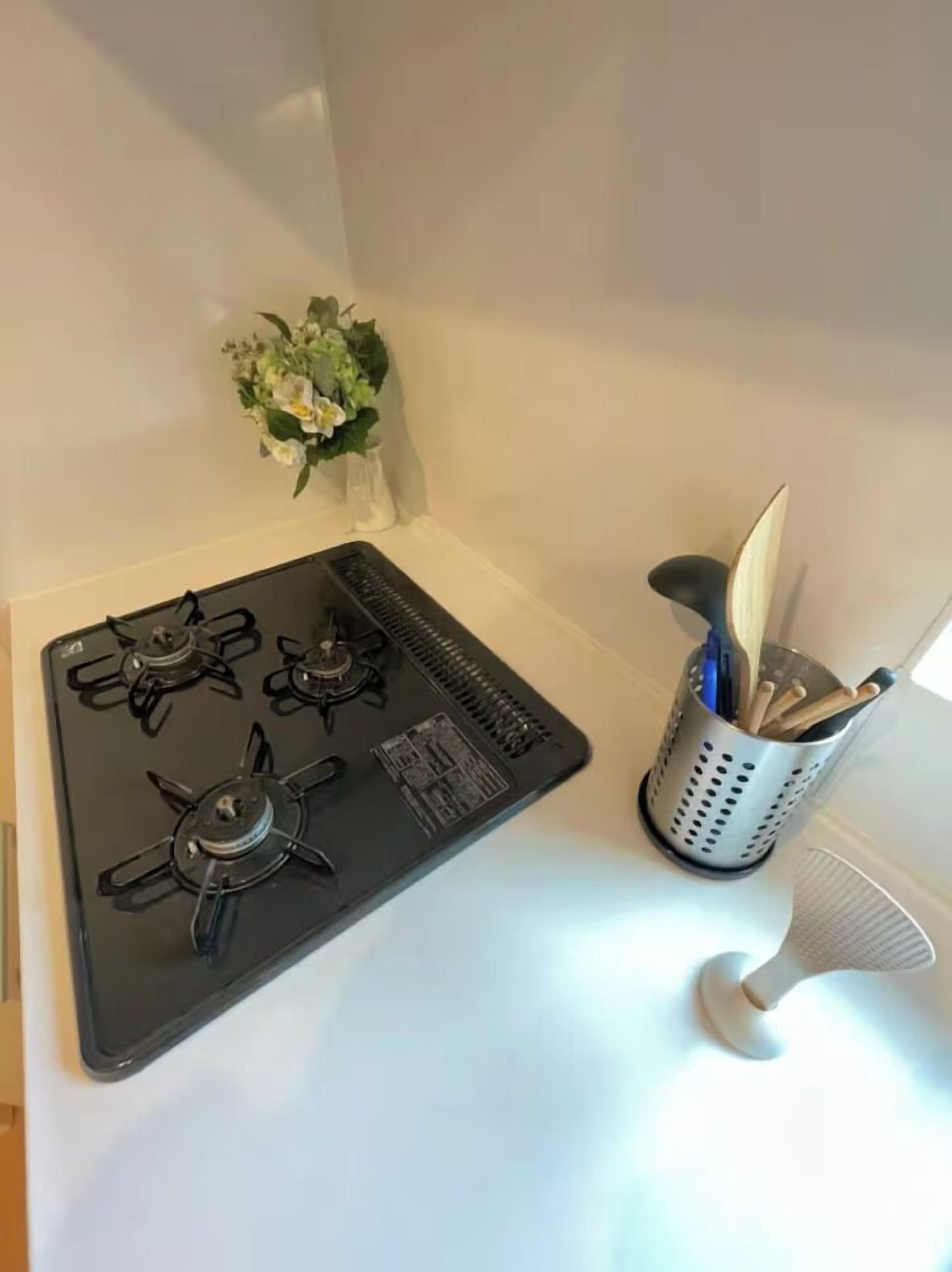 A kitchen with a black stove, a small vase with flowers, and a utensil holder.