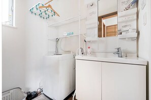 A white bathroom with a sink, mirror, and towel rack. - Haneda 5-chome (Tokyo)