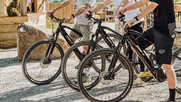 Three people with bicycles at a wooden archway with 'Greenfields Glamping' signage. - Greenfields Glamping Durbuy (Durbuy)
