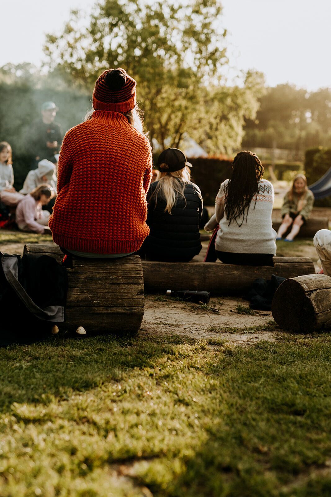 People sitting on logs in an outdoor setting.