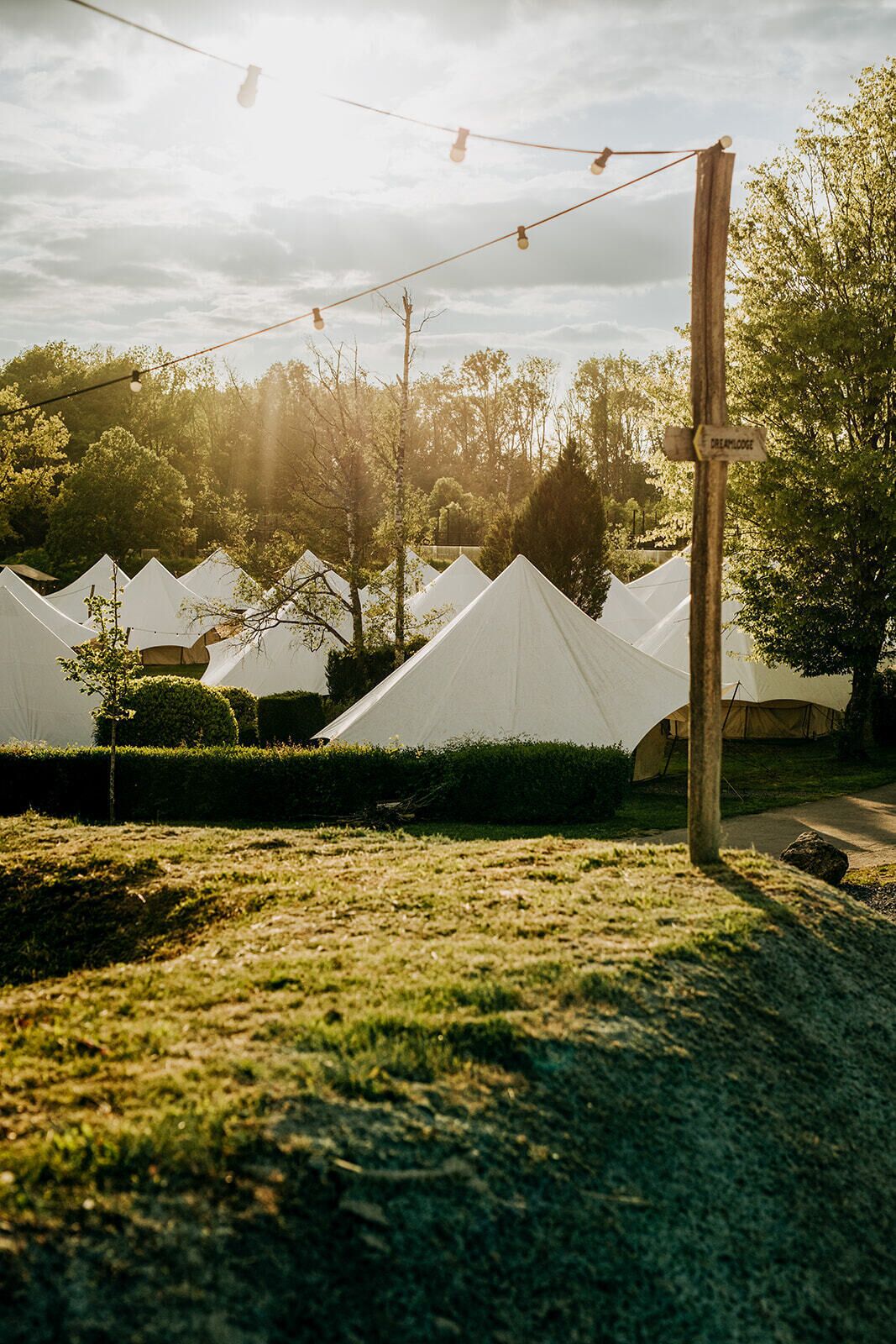 Een rij witte tenten met een bord waarop 'CAMPINGLODE' staat in de achtergrond.