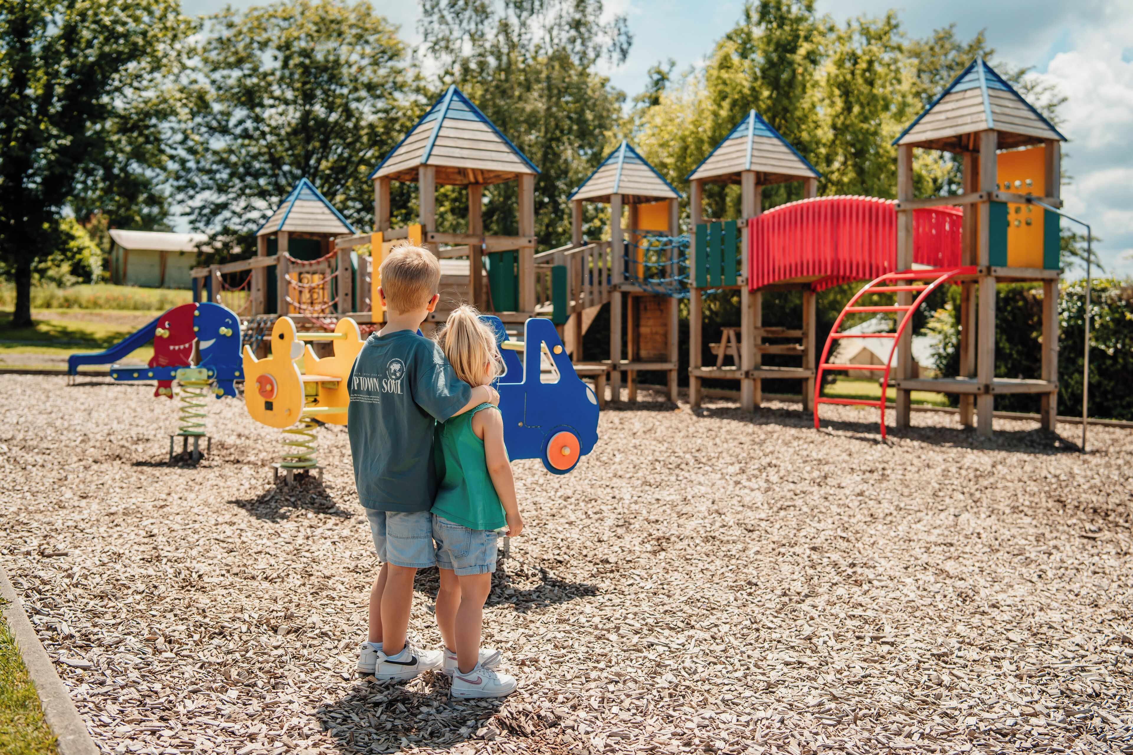 A playground with play structures and a wooden fence.