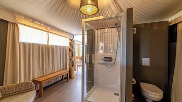 A room with a glass-enclosed shower, a wooden bench, a wicker sofa, and a view of the outdoors.