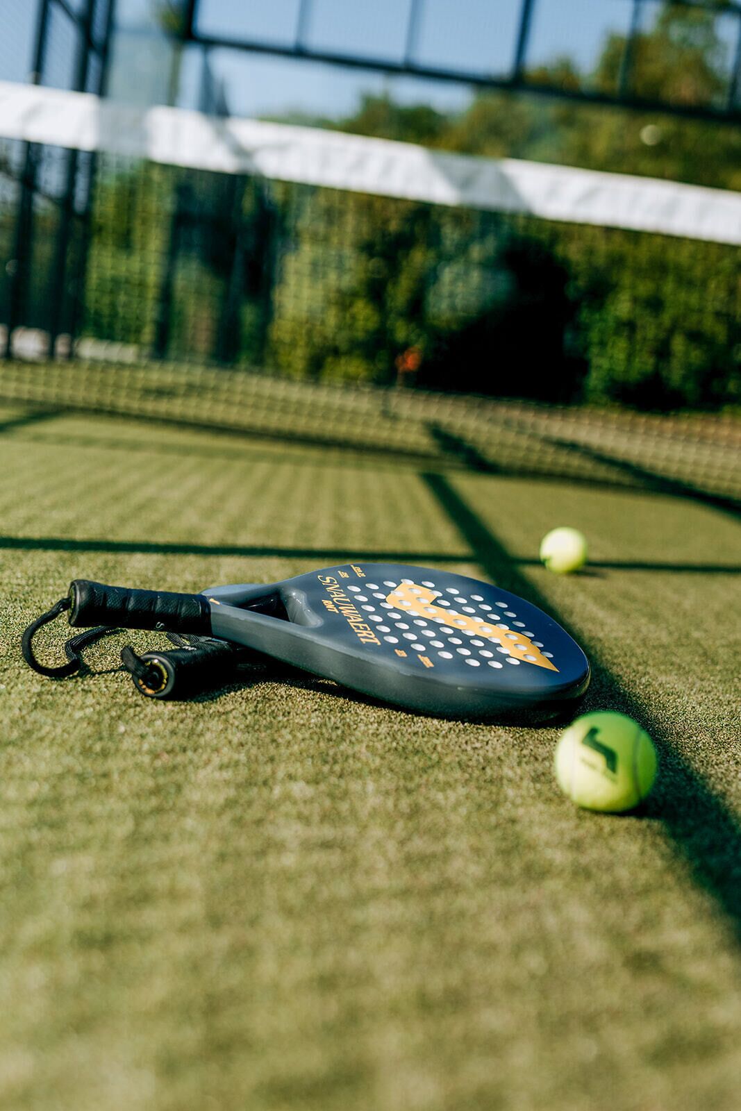 Een badmintonracket op een veld met een net en twee navels.