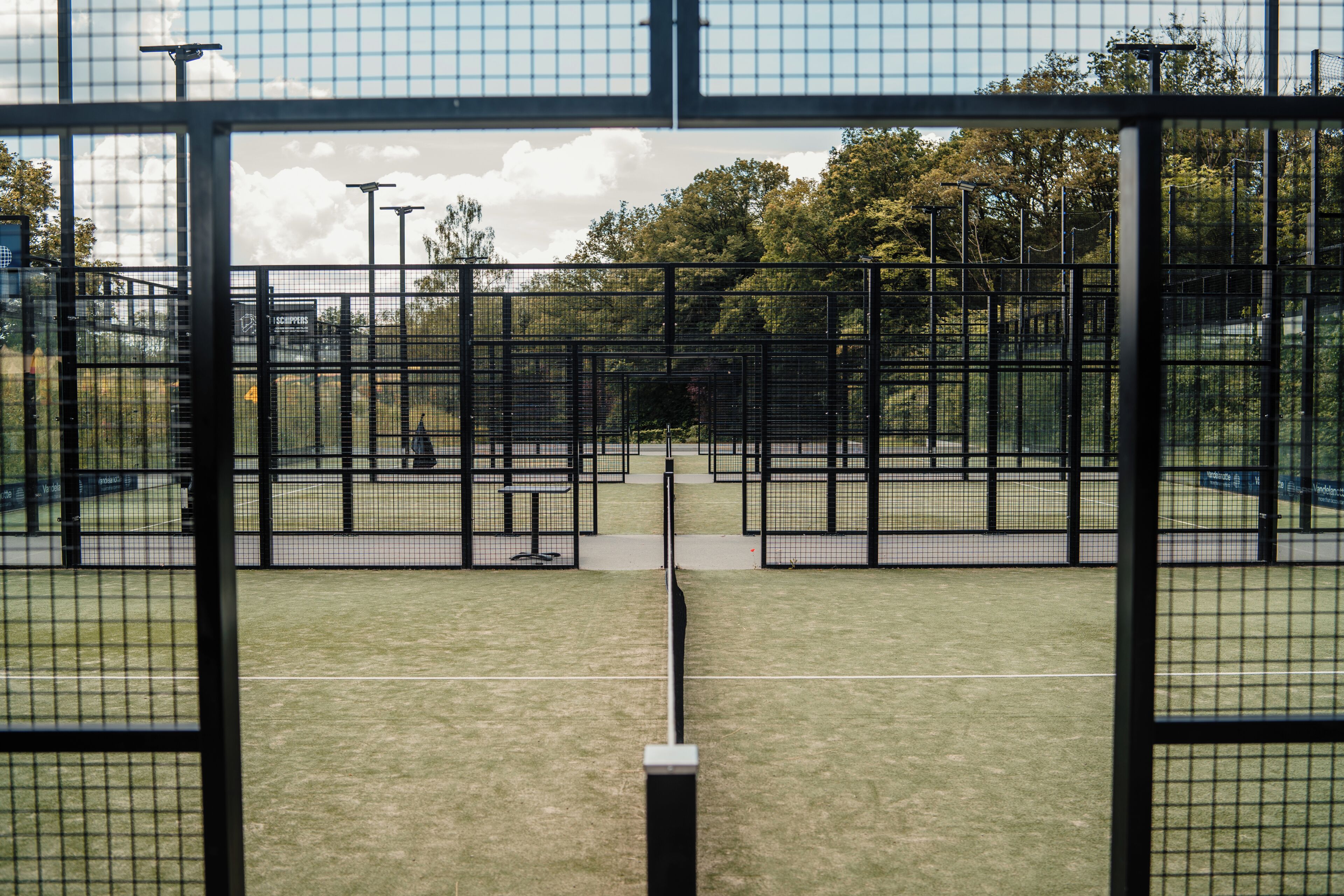 Un court de tennis avec un filet, entouré d’une clôture.