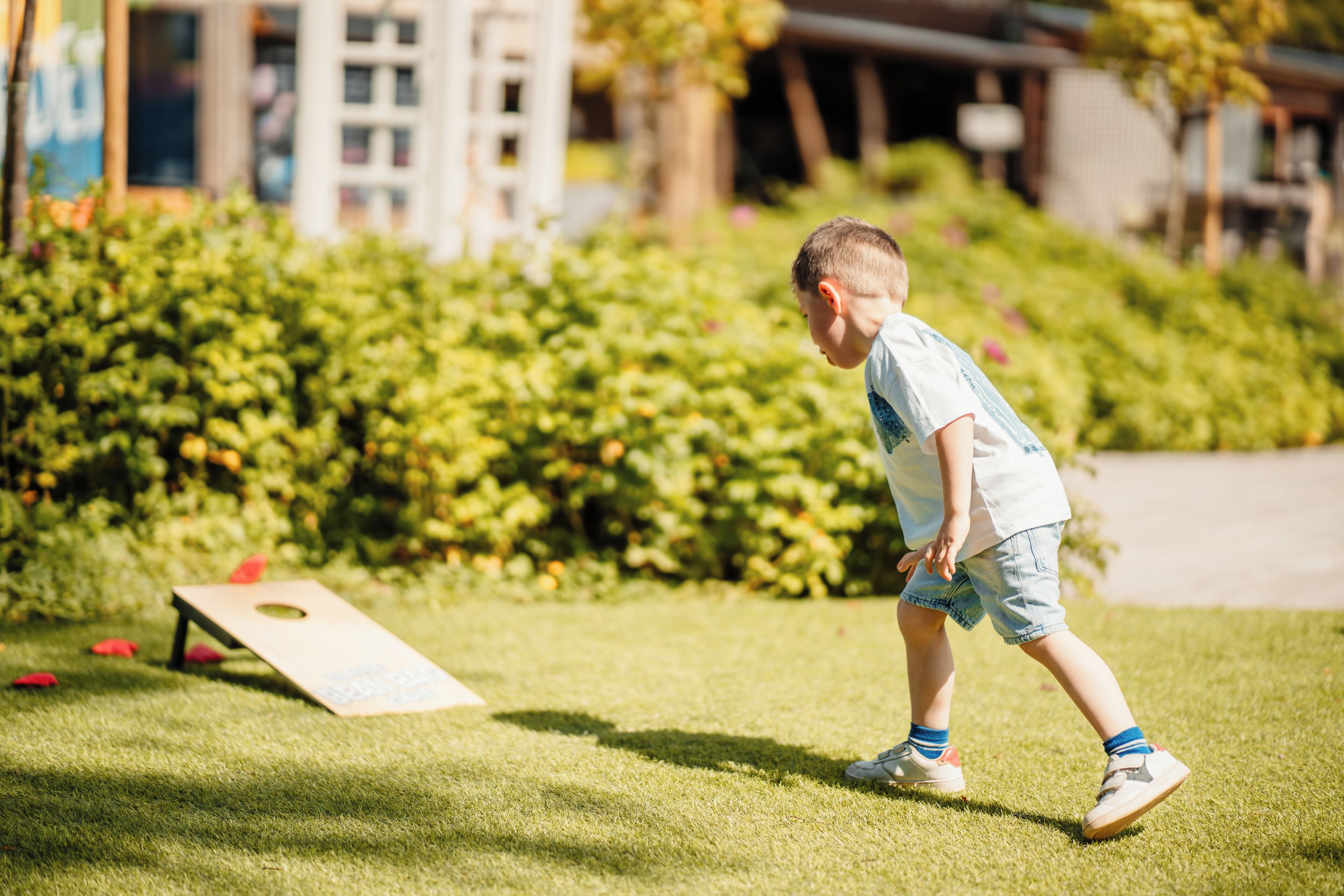 Un enfant joue sur une pelouse avec un jeu de société en bois.