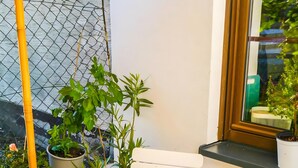 Une terrasse avec une table, des plantes en pot, une bouteille de vin et une chaise.