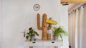 A white wall with a cactus decoration, a world map clock, and a sign that reads 'Le Verdon-sur-Mer.' - Chalet "Seafront" with Private Terrace, Garden and Wi-Fi (Le Verdon-sur-Mer)