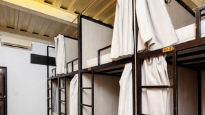 Stockbetten mit weißer Bettwäsche und Vorhängen, ein Holzboden und eine Decke mit einer Leuchte.
