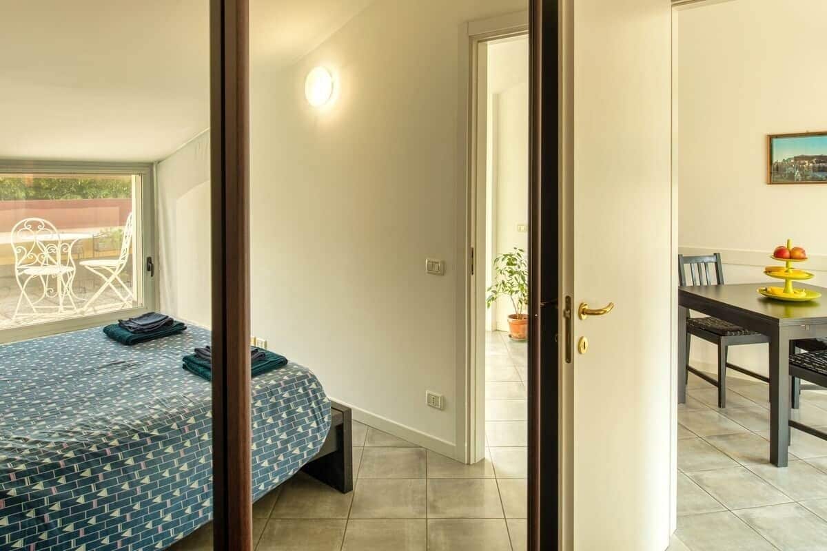 A room with a bed, a table with chairs, and a door leading to an outdoor area.