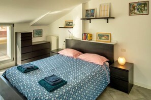 Una camera da letto con un letto, comodini, una cassettiera e mensole a parete con fotografie.