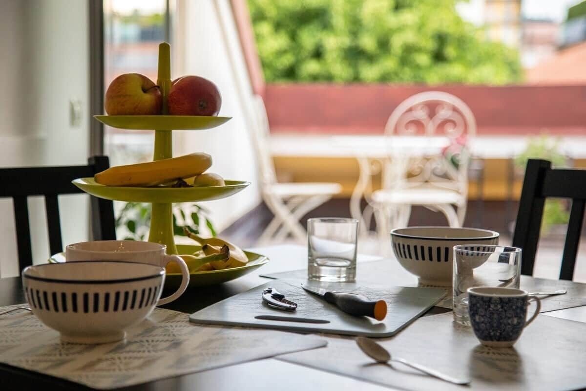 A dining table with a three-tiered fruit stand, bowls, cups, and a knife.