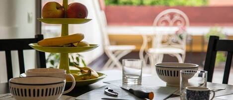 A dining table with a three-tiered fruit stand, bowls, cups, and a knife.