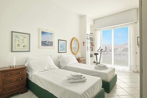 Une chambre d’hôtel avec deux lits, une commode en bois, un tapis de course et une grande fenêtre donnant sur un beau paysage.
