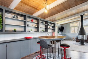 Une cuisine moderne avec des meubles gris, un îlot central en bois et des tabourets de bar rouges.