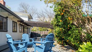 A deck with Adirondack chairs, a pergola, and a tree with oranges. - Spacious 4BR Backyard Oasis with BBQ Near UC Davis (Davis)