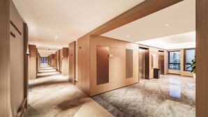 A hotel corridor with wooden paneling, a marble floor, and an elevator. - MEHOOD LESTIE Hotel(Xi'an Xixian Wuyue Plaza Afanggong South Metro Station Store) (Xi'an)