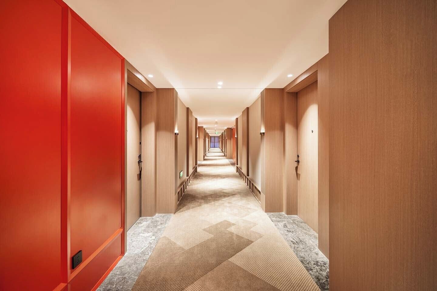 Un pasillo de hotel con suelo alfombrado, paredes de madera y puertas a ambos lados.