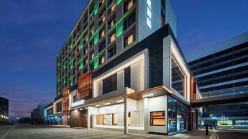 Un hotel moderno con varios pisos, ventanas amplias y una zona de entrada bien iluminada.
