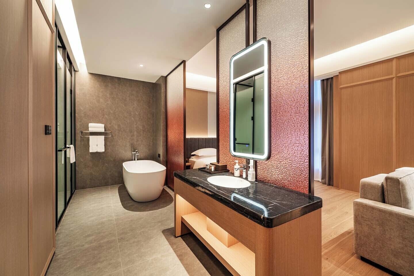 Une salle de bain moderne avec une baignoire sur pieds, un meuble-lavabo doté d’un grand miroir et des toilettes séparées.