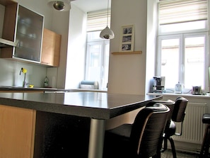 A kitchen with a central island, a coffee maker, and a toaster on the windowsill.