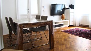 Ein Essbereich mit Holztisch und Stühlen, einem an der Wand befestigten Fernseher und einer Heizung.