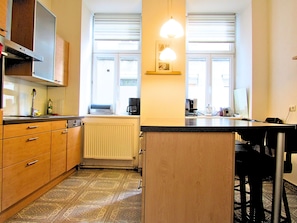 A compact kitchen with a central island, a built-in oven, and a radiator.