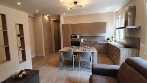 Eine moderne Küche mit integrierten Geräten, ein Essbereich mit Tisch und Stühlen sowie eine Sitzecke mit einer Couch.