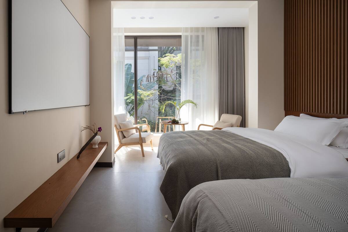 Ein modernes Hotelzimmer mit einem großen Bett, einem Schreibtisch und Blick ins Freie.