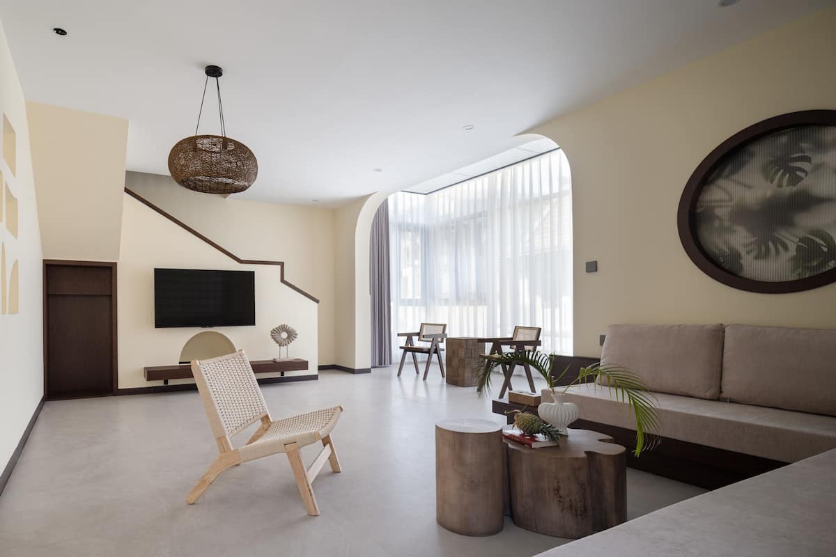 Ein modernes Wohnzimmer mit einer Couch, Sesseln, einem Fernseher und einer Treppe.