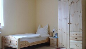 A bedroom with a wooden bed, a nightstand, a wardrobe, and a red rug.