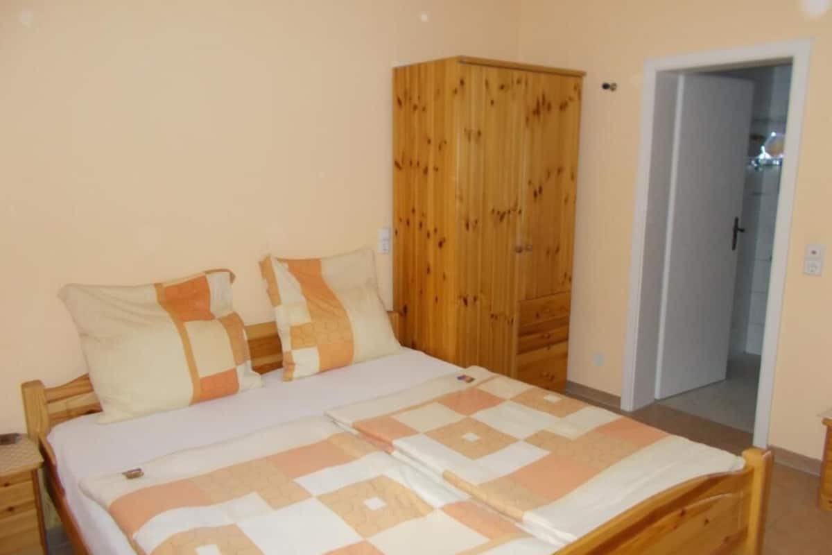 Un dormitorio con cama, armario de madera y puerta que da a otra habitación.