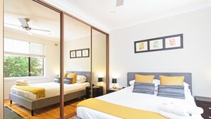 A bedroom with a large bed, bedside tables, a mirror, and framed artwork on the wall. - Home among the Gum Trees - free wine (Tea Tree Gully)