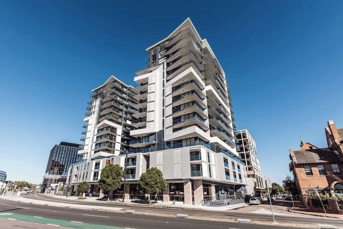 A multi-story building with balconies, a modern architectural design, and a clear sky.